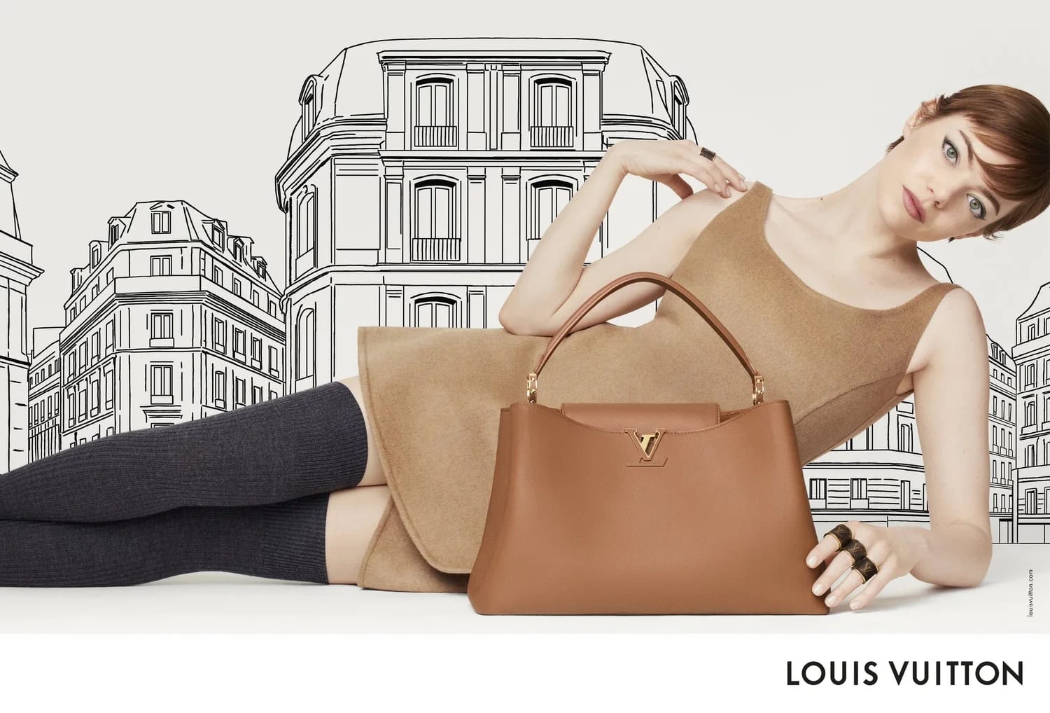 Fashion ad featuring a model lying with a light brown leather handbag, set against a black and white Paris cityscape backdrop.