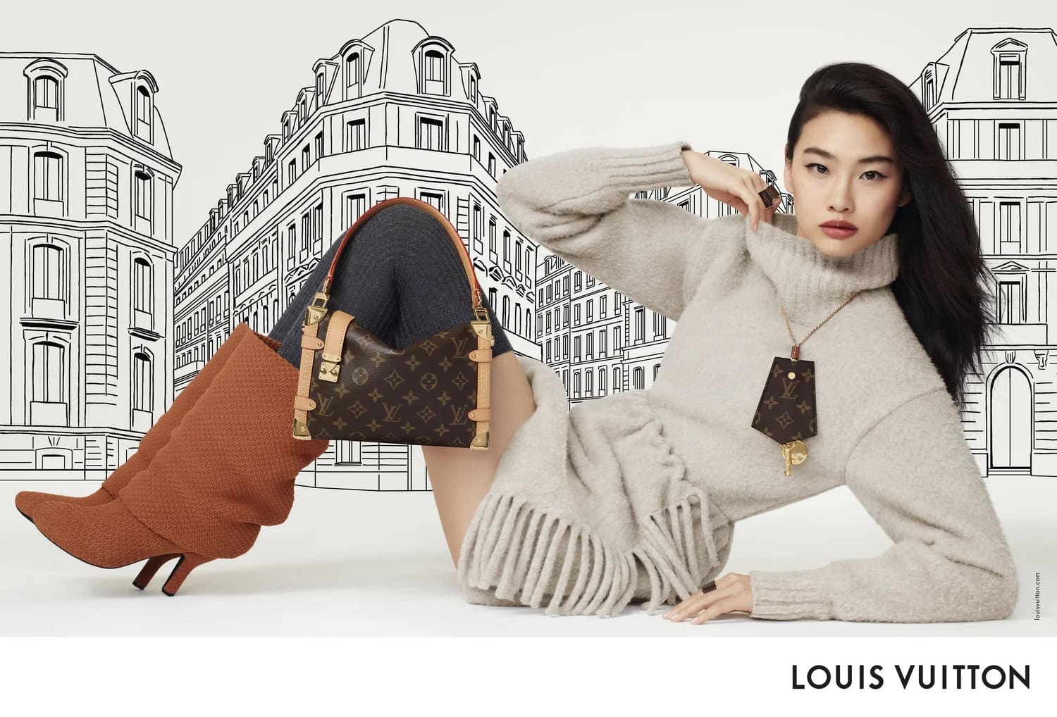 Fashion shot: Woman poses with Louis Vuitton handbag and pendant. She wears a sweater, gray leggings, orange boots against illustrated city.