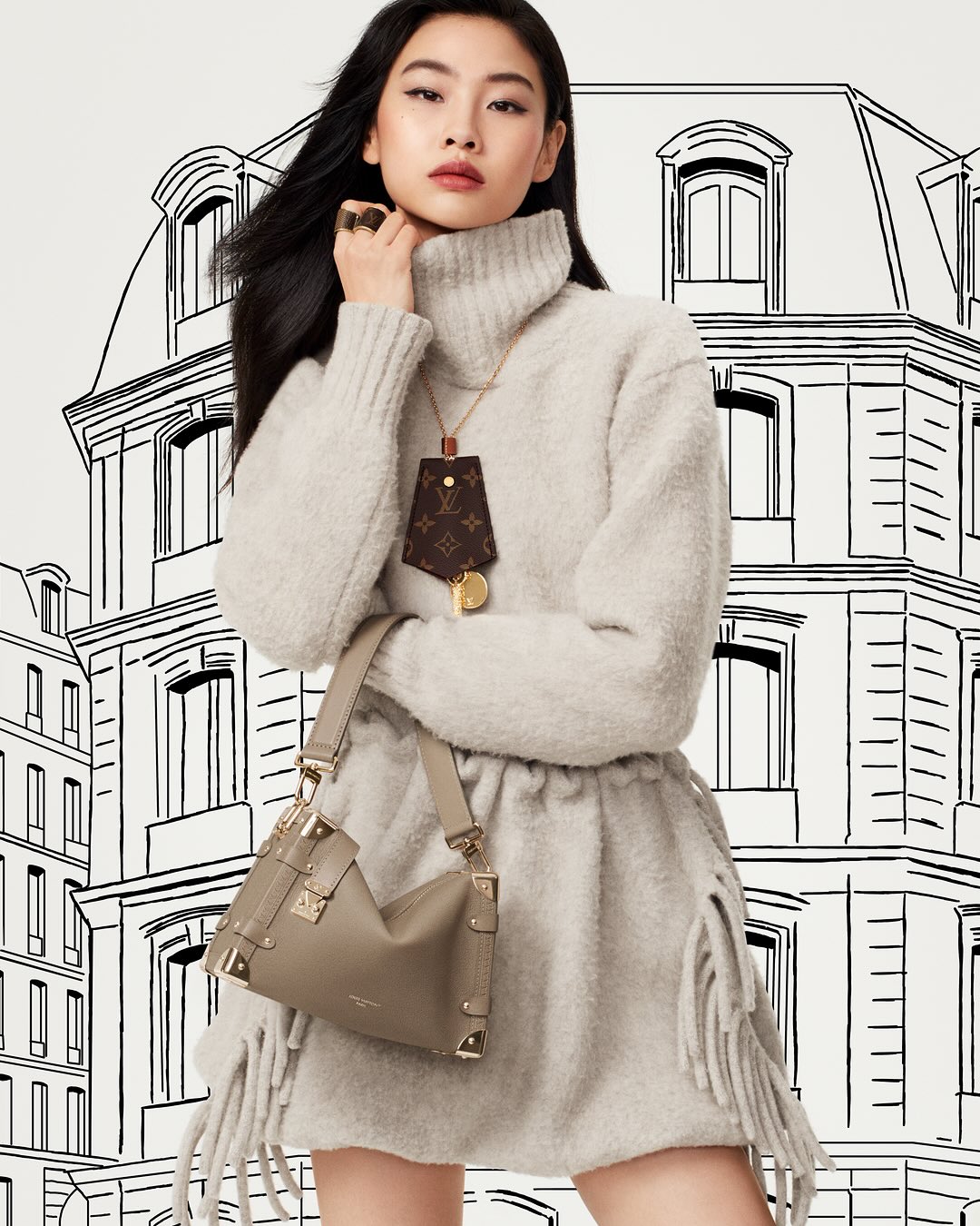 Asian female model wearing a neutral-toned turtleneck sweater dress and a Louis Vuitton purse against a building illustration.