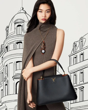 Asian woman models a black leather handbag with gold logo in a fashion shot against a stylized cityscape backdrop.