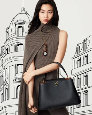 Asian female model wearing brown knit turtleneck dress holding a black leather handbag against illustrated background