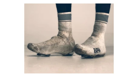 Close-up of muddy cycling shoes and striped socks on a cyclist for Rapha, photographed by Dima Hohlov.