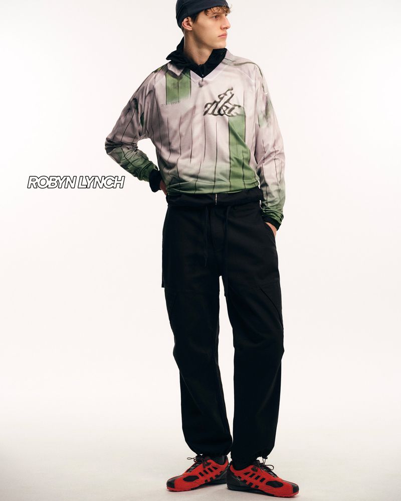 Model wearing patterned athletic top and black trousers against white background for Robyn Lynch lookbook