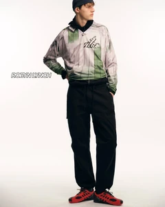 Model wearing patterned athletic top and black trousers against white background for Robyn Lynch lookbook