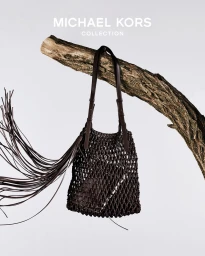 Dark brown leather woven shoulder bag hanging from a gnarled tree branch against a pale background