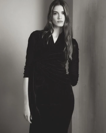 Monochrome portrait of a model wearing a dark long-sleeve dress against a neutral studio background.