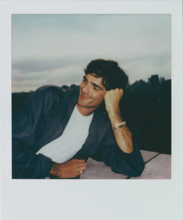Jacob Elordi leaning on a ledge with a city skyline behind him in a polaroid photograph for Cartier Love Unlimited.