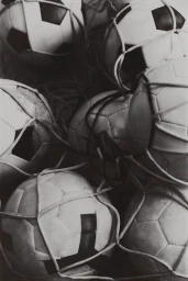 Monochrome close-up of multiple soccer balls tangled in netting from the A Roar Beyond Time project by David Portela.