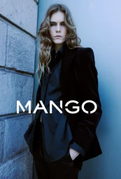 Model with long wavy hair wearing a black blazer and shirt against a stone wall and blue background with Mango text overlay