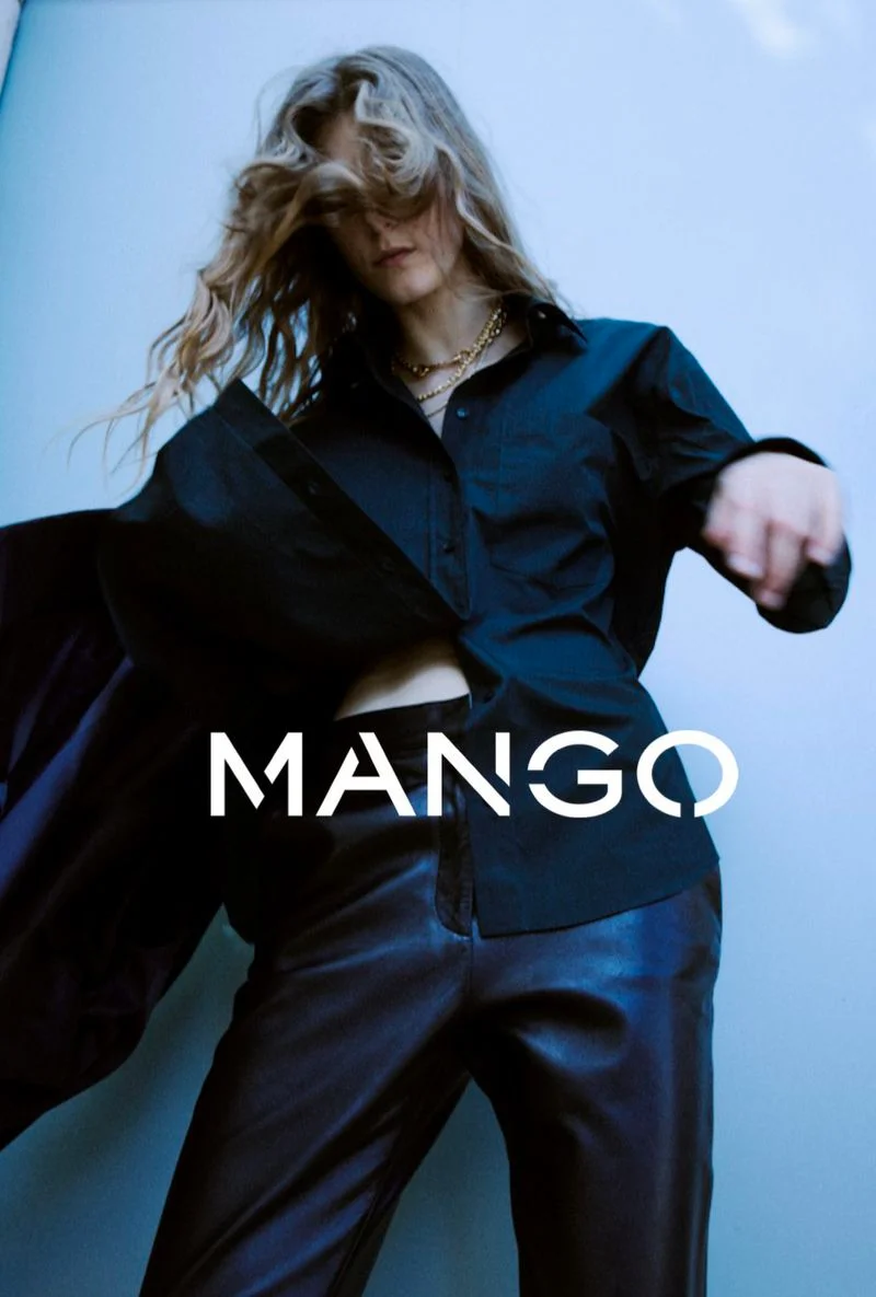 Model in a black button-down shirt and dark trousers against a pale blue background with Mango text overlay