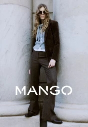 Model in sunglasses wearing a brown blazer and trousers standing against massive stone columns for a Mango campaign.