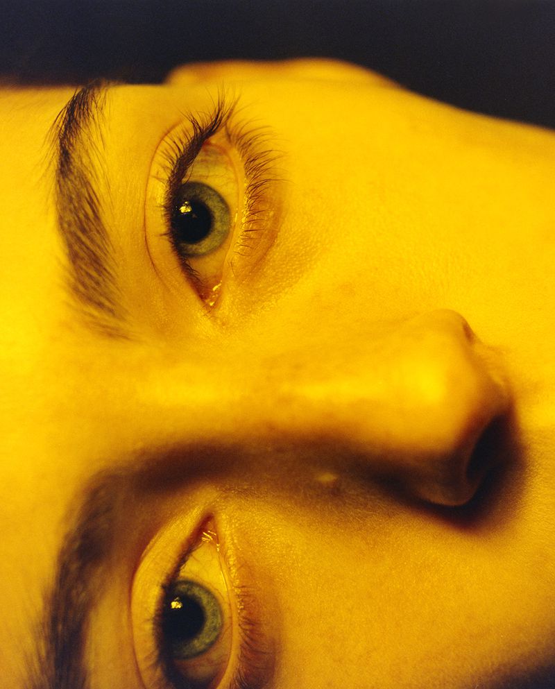 Close-up studio shot of a fair-skinned adult with striking green eyes under warm lighting, emphasizing beauty and detail.