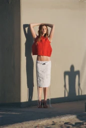 Model Lulu Tenney posing against a wall wearing a red top and white skirt for WSJ Uptown Surf
