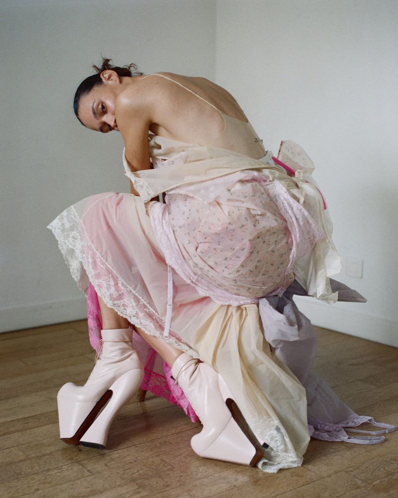 Model Binx Walton wearing a layered pastel dress and chunky heels, captured in an editorial shoot by Senta Simond.