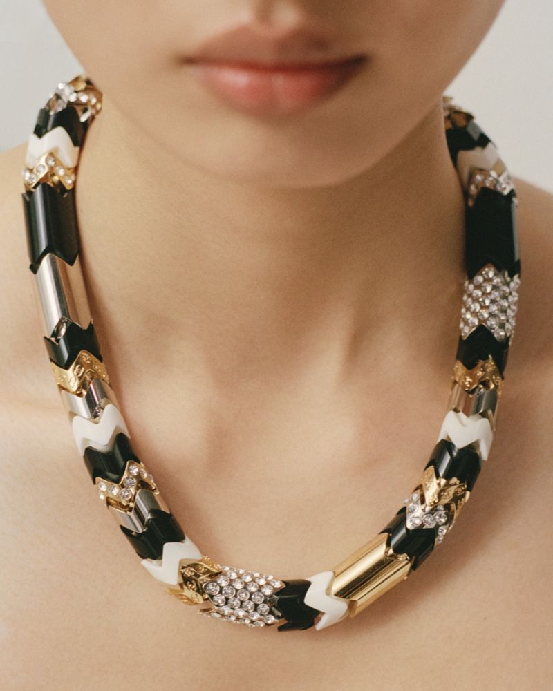 Close-up of a model wearing a chunky black, white, and gold patterned statement necklace for Muse Magazine.