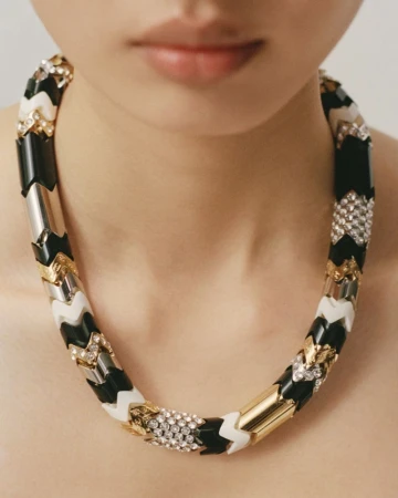 Close-up of a model wearing a chunky black, white, and gold patterned statement necklace for Muse Magazine.