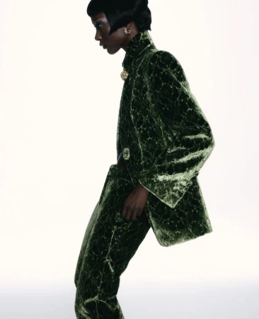 Model Mahany Pery wearing a textured green velvet suit against a bright white background for Elle Brasil