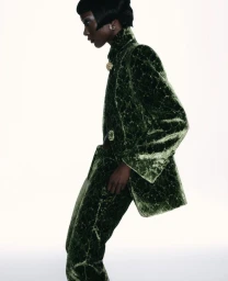 Model Mahany Pery wearing a textured green velvet suit against a bright white background for Elle Brasil