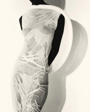 Model Mahany Pery in a sheer textured dress wearing a sculptural white neck ring against a white background for Elle Brasil