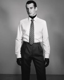 Model in white shirt with patterned tie and black gloves against a grey background