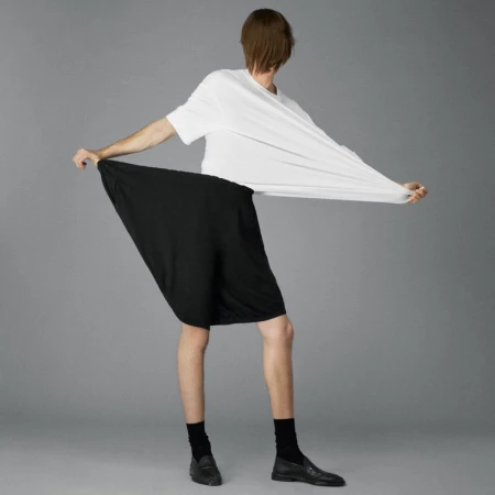 Model stretching a white t-shirt and black shorts against a grey seamless studio backdrop