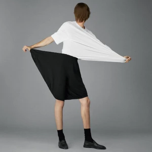 Model stretching a white t-shirt and black shorts against a grey seamless studio backdrop