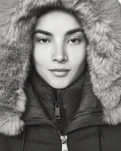Close-up portrait of a woman wearing a heavy puffer jacket with a large fur-trimmed hood.