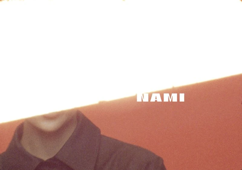 Close-up of an adult wearing a dark button-down shirt against an orange backdrop, with bright white light and the text 'NAMI'.