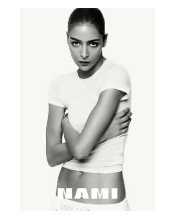 Monochrome portrait of a female model in a white t-shirt with crossed arms and neutral expression, against a plain white backdrop with text.