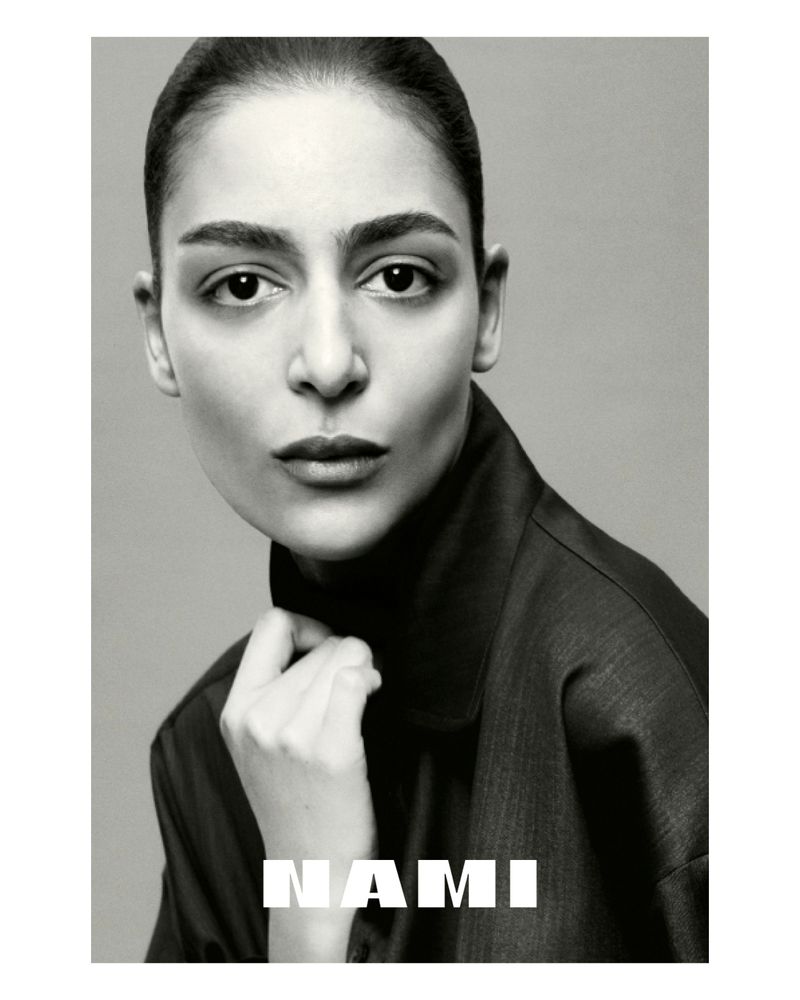 Monochrome portrait of a woman with a neutral expression, wearing a dark collared shirt against a plain background, featuring the text 'NAMI'.