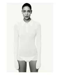 Model Nora Attal wearing a white long-sleeve polo top against a plain white studio background for Nami Drop 4.