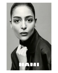 Portrait of model Nora Attal wearing a dark collared top against a plain grey background for Nami