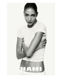 Model Nora Attal wearing a fitted white t-shirt against a clean white seamless studio background for Nami.