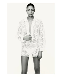 Model Nora Attal wearing a white patterned shirt for Nami Drop 4 against a bright seamless white background