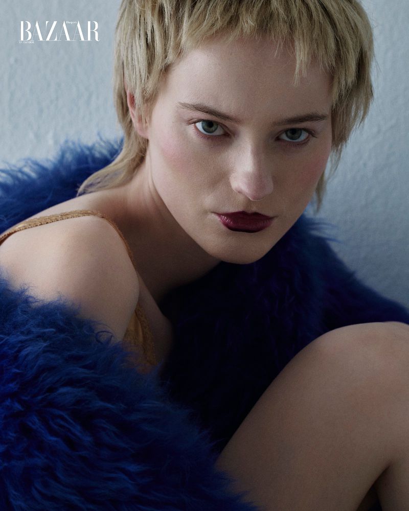 Close-up portrait of a woman with short blonde hair and dark lipstick wearing a blue faux fur coat, fashion editorial, beauty shot.