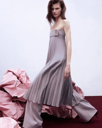 Model in a strapless pleated mauve dress and wide leg trousers posing over pink paper sculptures for Harper's Bazaar Serbia