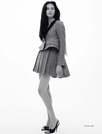Full-length portrait of a young Asian woman wearing a gray tweed skirt suit and black heels, posing in front of a white backdrop.