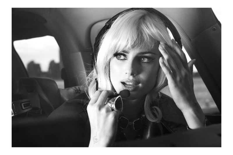 Black and white portrait of a fair-skinned woman with platinum blonde hair, wearing a headset with a microphone inside an aircraft.