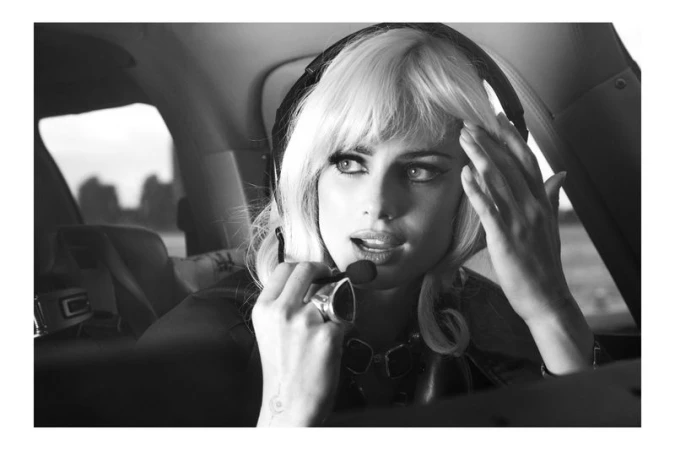 Black and white portrait of a fair-skinned woman with platinum blonde hair, wearing a headset with a microphone inside an aircraft.