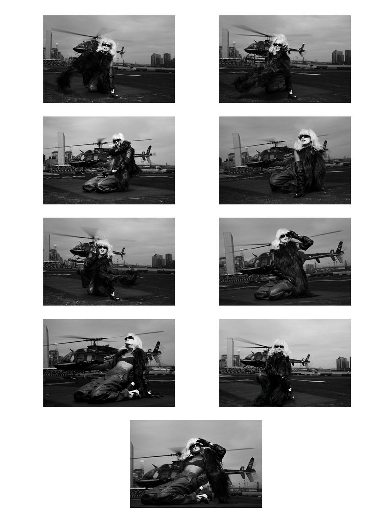 Monochrome fashion shot of a person with long blonde hair, wearing a dark jacket, posing in front of a helicopter and city skyline.