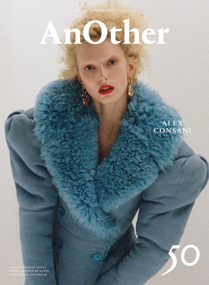 Magazine cover featuring a young woman with curly blond hair, red lipstick, and a blue fur-collared coat against a plain white background.