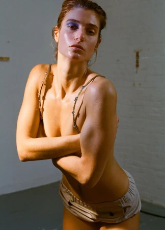 Model with blue eyeshadow and chained straps posing against a neutral wall for an AnOther Magazine editorial by Brianna Capozzi