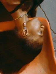 Close-up portrait of a model wearing a gemstone necklace and drop earring in an editorial shoot for AnOther Magazine and Prada.