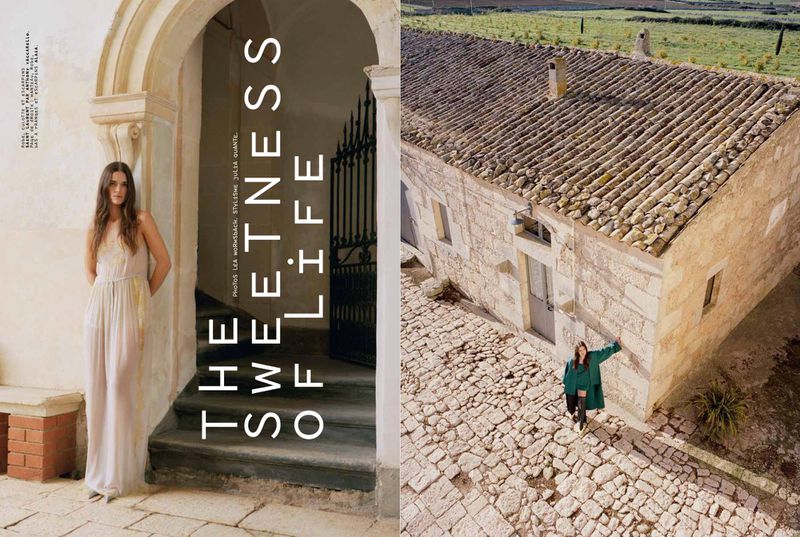 Fashion editorial image featuring a woman in a flowing gown in an arched doorway and a woman in green standing near stone building.