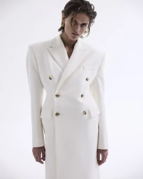 Model wearing a structured white double-breasted blazer dress against a clean white background.