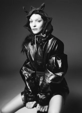 Model Mariacarla Boscono in a dark hooded jacket against a grey background for D Repubblica shot by Karim Sadli.
