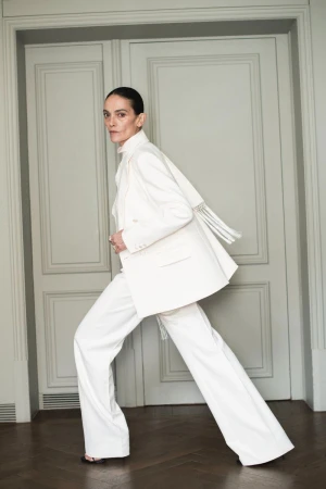 Model Laura Ponte in a white pantsuit posing in front of double doors for Mango capsule collection