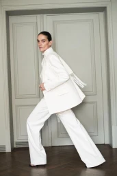 Model Laura Ponte in a white pantsuit posing in front of double doors for Mango capsule collection