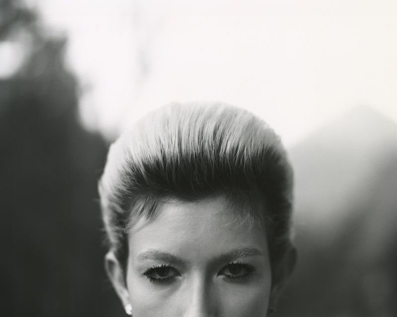 Close-up portrait focusing on the eyes and styled hair of a model against a soft-focus background