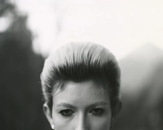 Close-up portrait focusing on the eyes and styled hair of a model against a soft-focus background